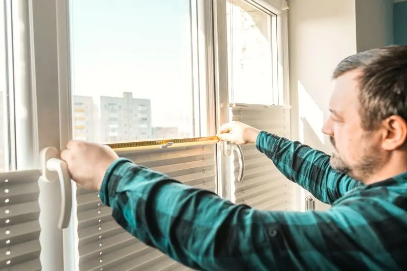 Installer measuring a window with a tape measure
