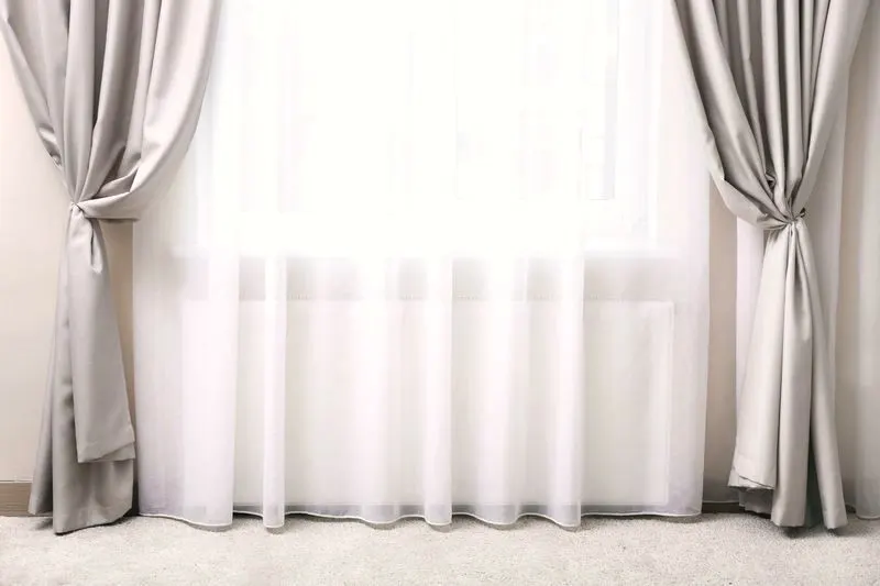 Floor-length drapery panels framing white sheers