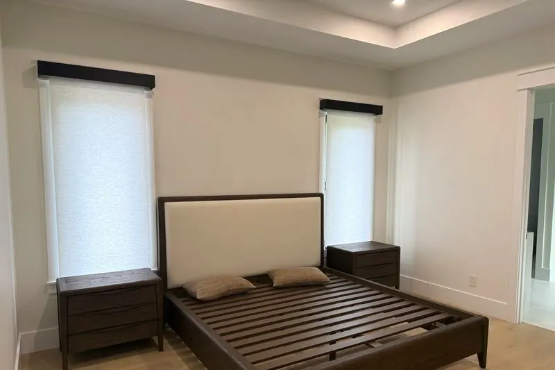 Bedroom with light filtering roller shades under dark valances on both windows