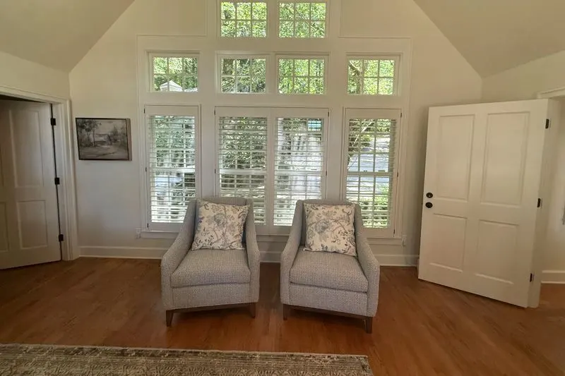 Plantation shutters on a wall of windows in a vaulted sitting room
